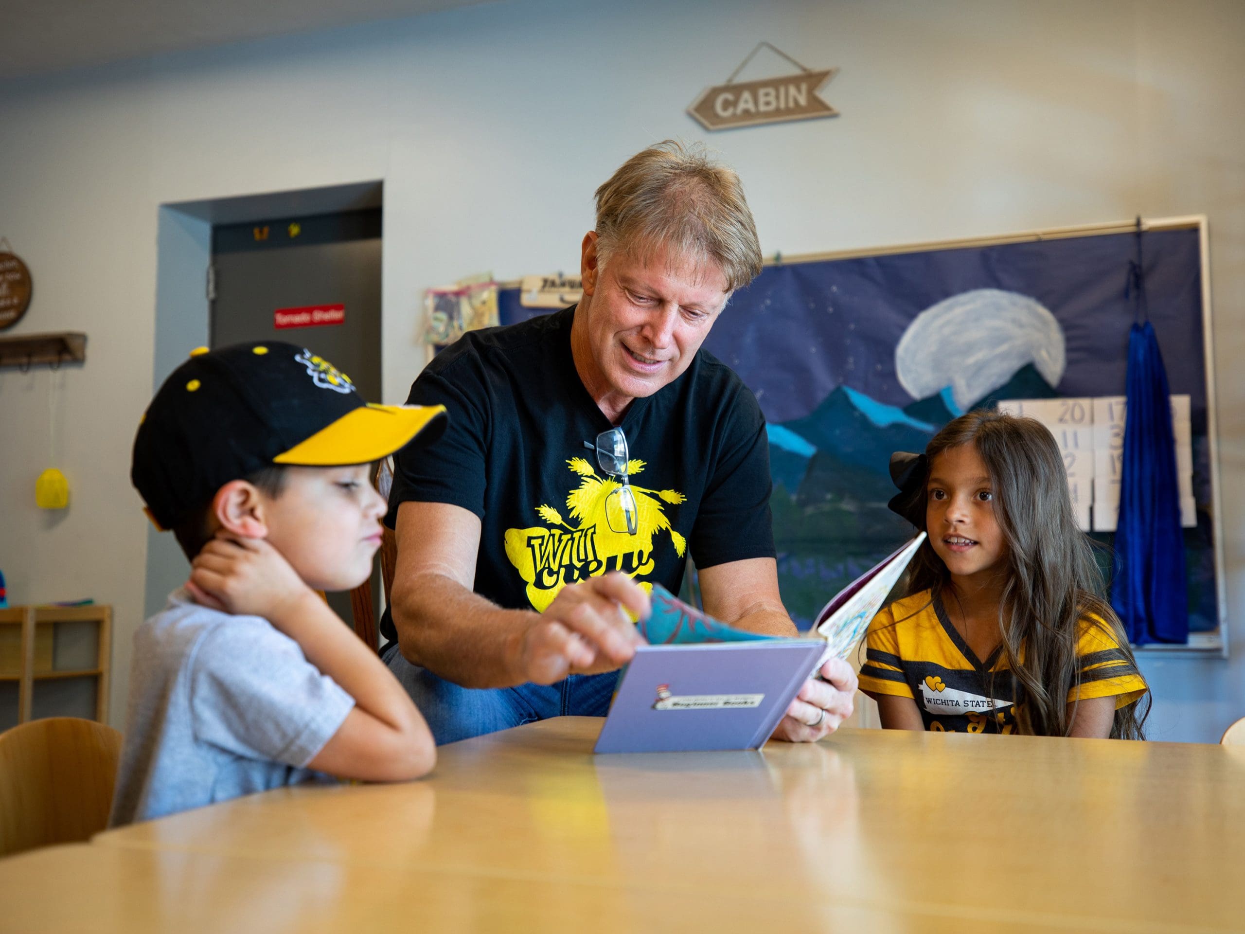 First gentleman Rick Case reads a book to two children as a volunteer for Wu Crew Reads.