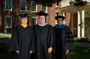 Picture of Faculty/staff members standing in front of a building wearing regalia.