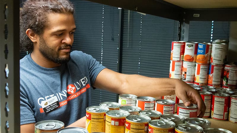WSU employee stocking canned food items.