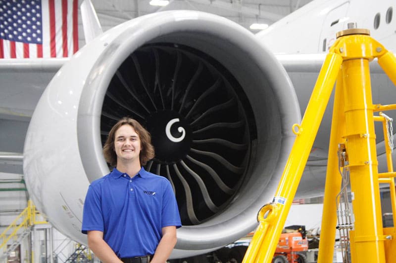 Picture of Wichita State senior Preston Keasey, majoring in mechanical engineering, in front of jet engine.