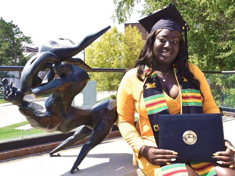 Aunjnae White, a first-generation student, poses with her degree in psychology.