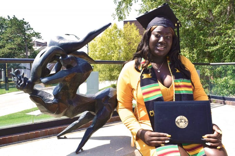 Aunjnae White, a first-generation student, poses with her degree in psychology.