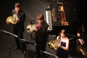 Picture of three Wichita State students playing the French Horn.