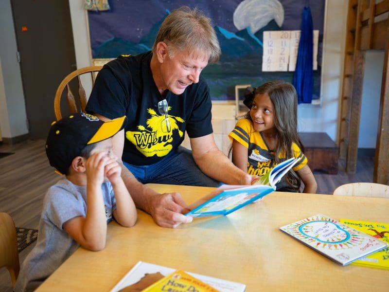 Picture of Rick Case reading to two children as part of Wu Crew Reads.