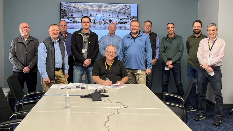 Members of Boeing pose around conference table.
