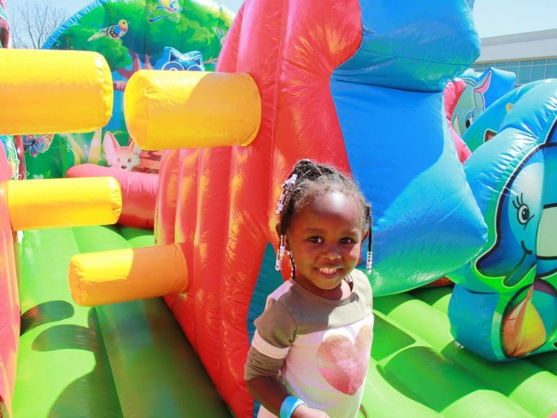 Child playing on brightly-colored inflatable moon bounce obstacle course.