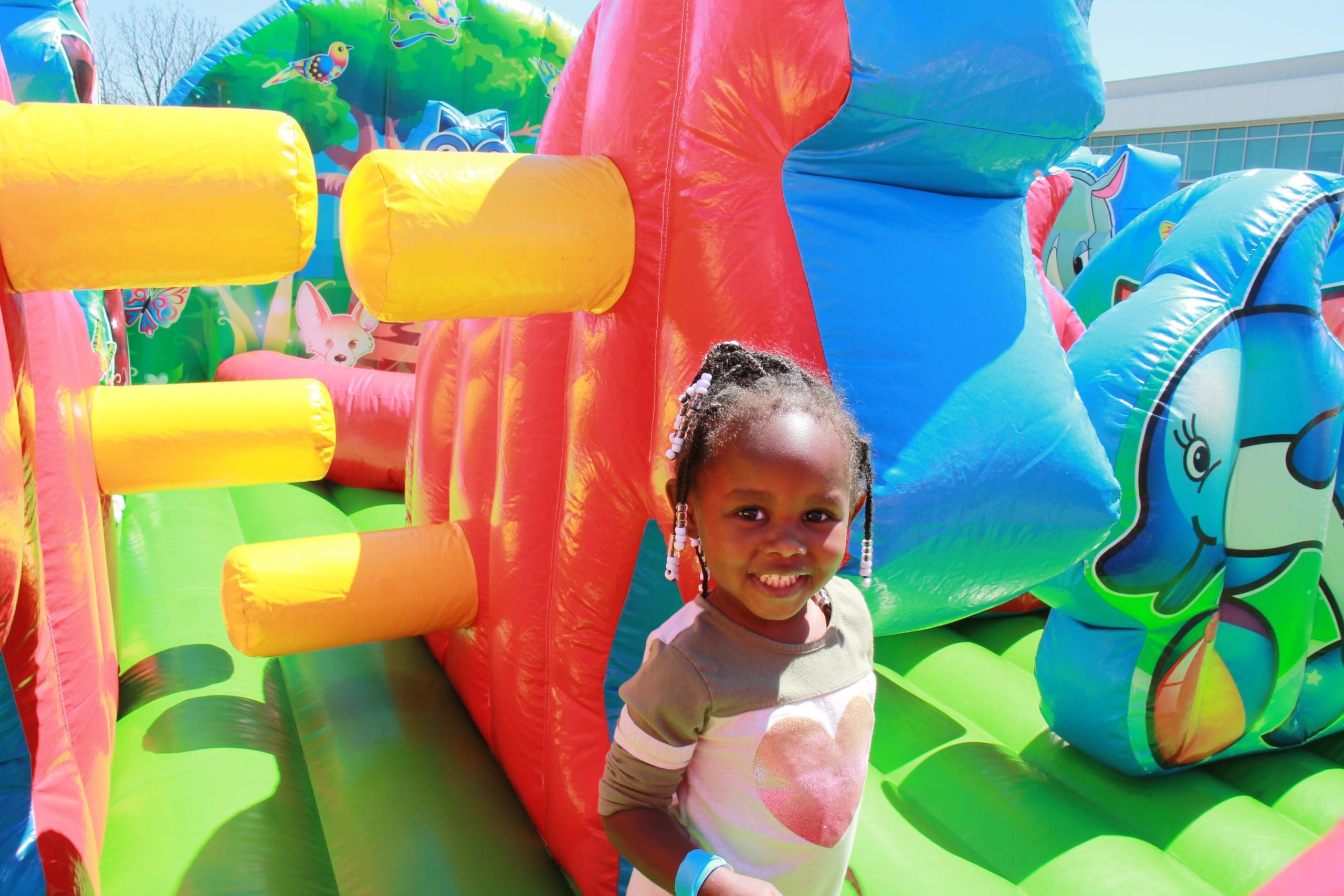Child playing on brightly-colored inflatable moon bounce obstacle course.