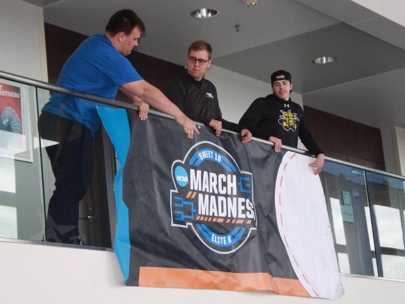 Wichita State students Mason Burden (left), Jordan Emerson (middle) and Nate Rundell are among the students in the sport management program helping with NCAA Tournament preparations at Intrust Bank Arena. Students work in several areas during the set-up, practices and games.