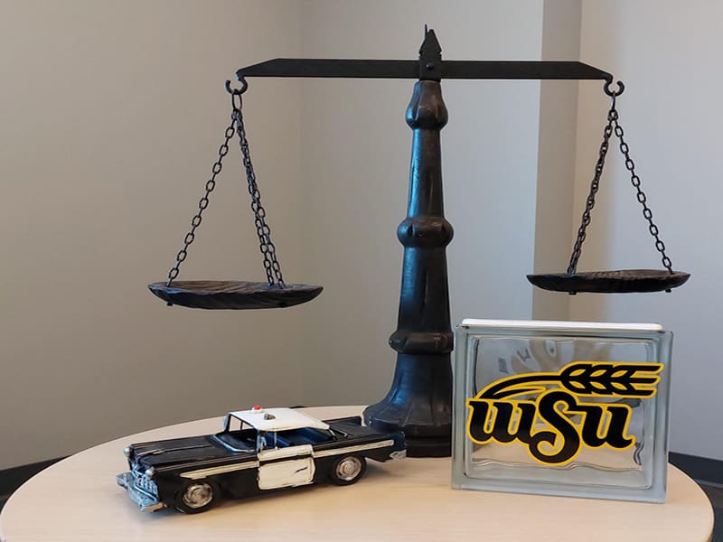Picture of scales, miniature police car and WSU plaque on desk.