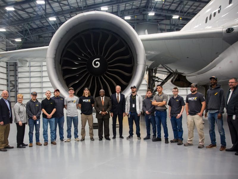 Picture of FAA deputy administrator Bradley Mims and U.S. Senator Jerry Moran with NIAR members in front of jet engine inside NIAR facility.