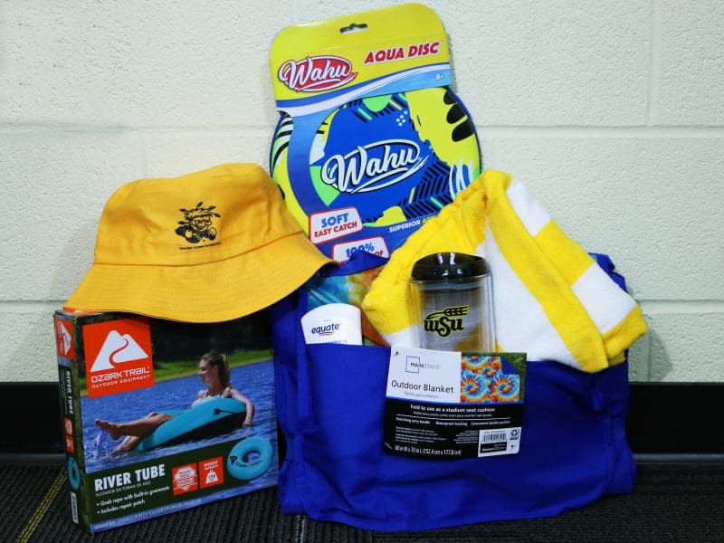 The picture includes an SCA bucket hat and tumbler, beach towel, outdoor blanket, water frisbee, sunscreen, and a river tube.