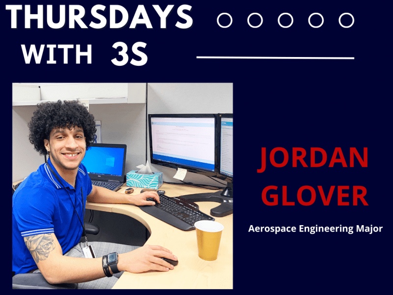Jordan Glover sits at his cubicle at 3S. TEXT: Thursdays with 3S/ Jordan Glover / Aerospace Engineering Major
