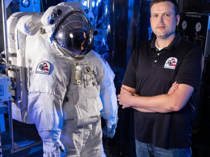 Image of Dr. Ryan Amick next to empty space suit.