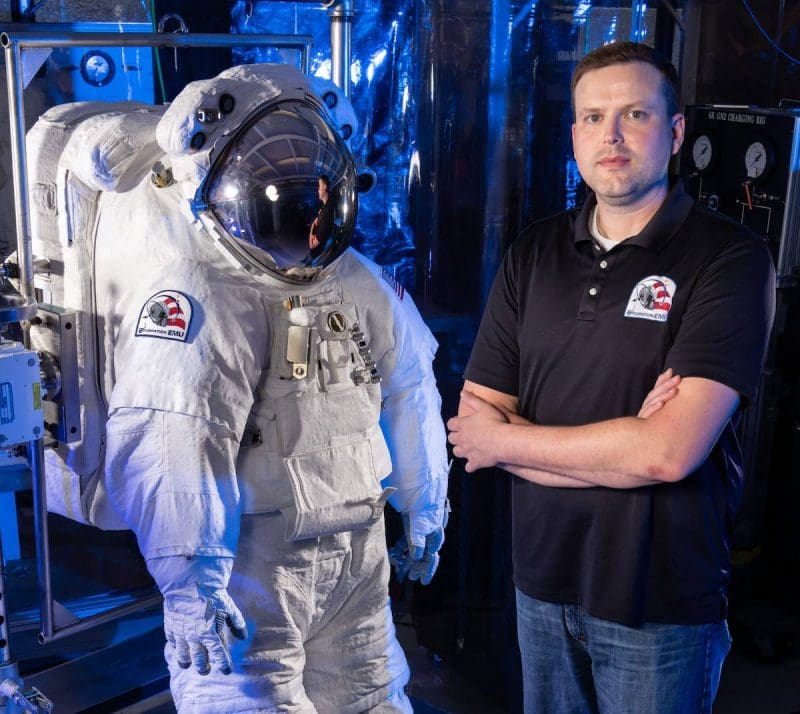 Image of Dr. Ryan Amick next to empty space suit.