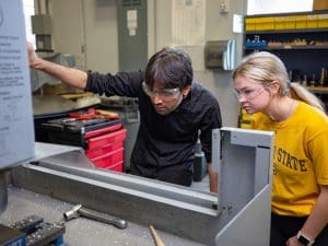 Image of two WSU engineering students working on large piece of equipment.
