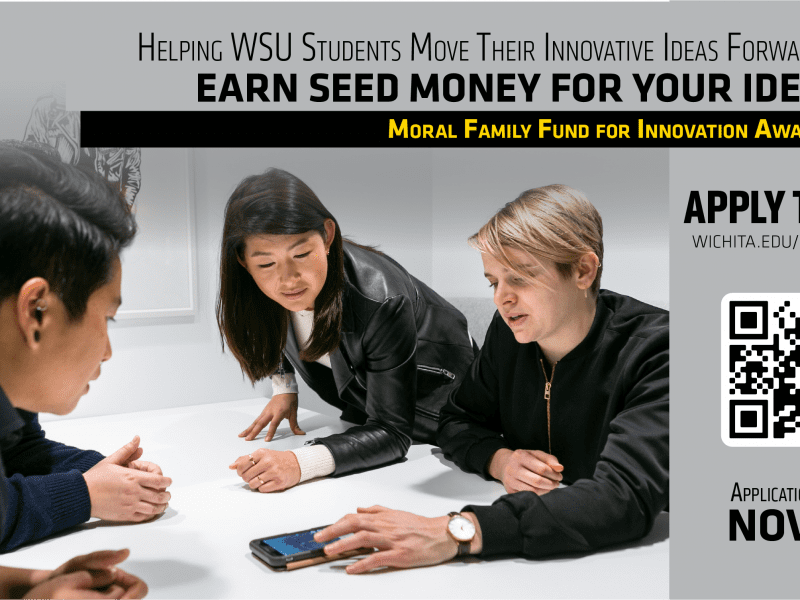 "Helping WSU Students move their innovative ideas forward. Earn seed money for your idea. Moral Family Fund for Innovation Award. Apply Today! wichita.edu/moral-fund. Applications Due: Nov 18" Four people sit around table leaning forward to look at something being shown on a phone.