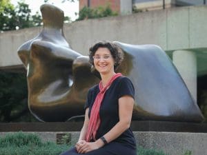 Photo of Ulrich Curator Ksenya Gurshtein with the "Reclining Figure" sculpture by Henry Moore in front of the Ablah Library as the backdrop.
