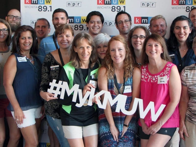 A photo of a group of KMUW volunteers holding a "#MyKMUW" sign..