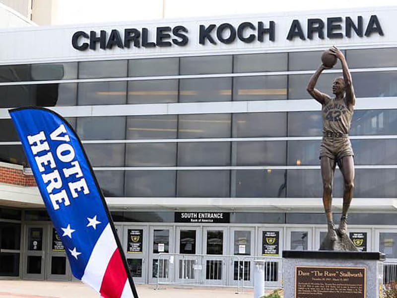 Photo of the Dave "The Rave" Stallworth of the statue in front of Charles Koch Arena with a flag with the text, "Vote Here."