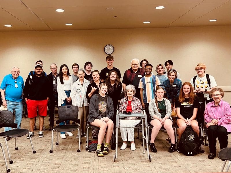 A group picture of WSU students and Larksfield residents posing together in a conference room at the Rhatigan Student Center.