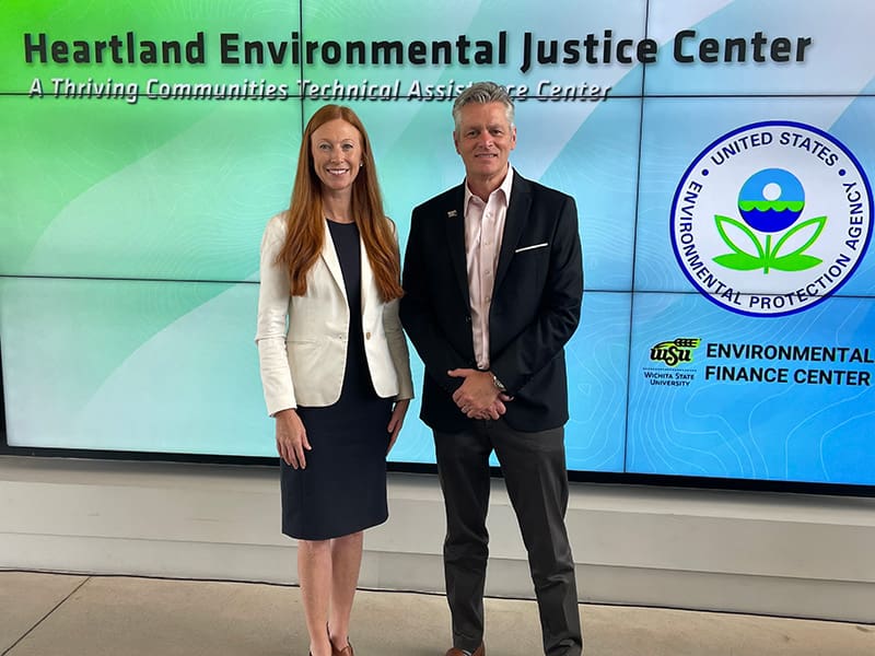 Meg McCollister and President Rick Muma post in front a Heartland Environmental Justice Center digital sign