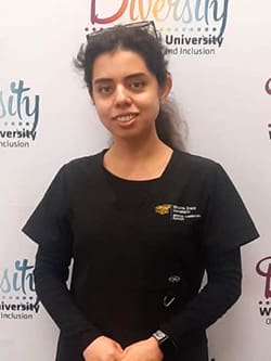 Fatemeh Farokhi stands in front of a WSU Diversity, Equity and Inclusion poster