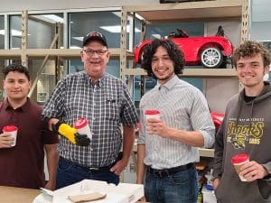 Students in the 3D Printed Prosthetics organization pose in their workshop with a client using one of their 3D printed prosthetics