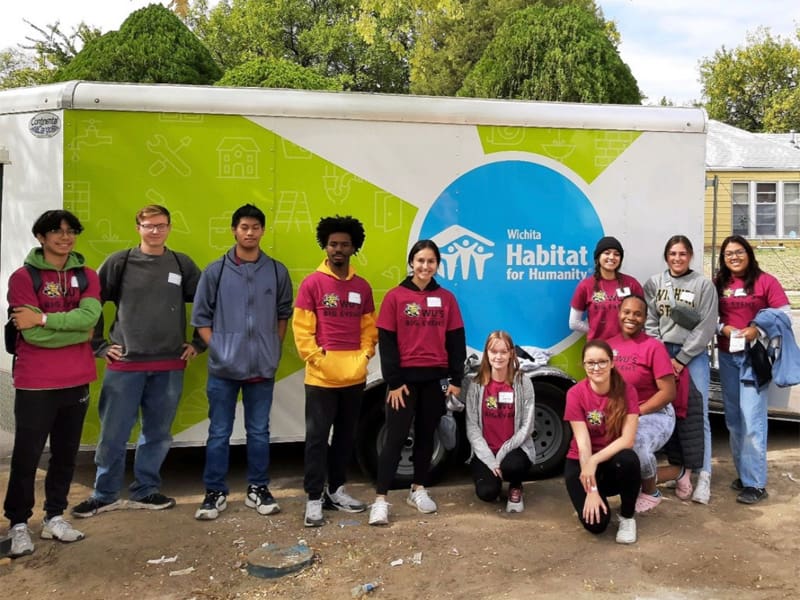 Members of the Community Service Board stand in front of a Habitat for Humanity van