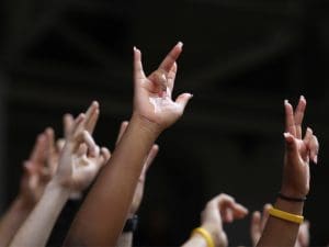 Students raise the Shockers hand sign at an athletics event