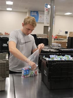 Picture of a student filling a gallon sized bag of food at the Kansas Food  Bank Warehouse