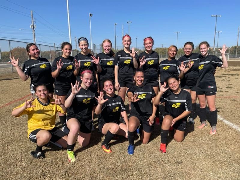 The Women's Soccer Club pose with the Shockers sign for a photo