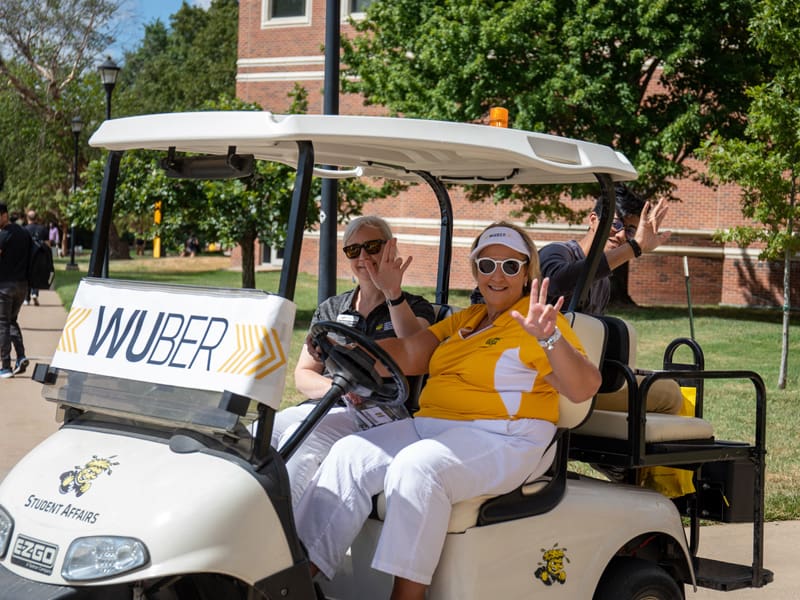 WSU staff members giving a ride to a student in their WUBER golf car