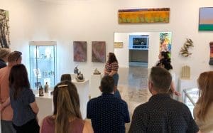 A group of people look at ceramic artwork in a gallery.