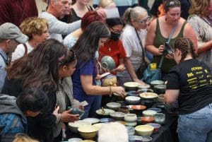 A crowd of people choose a bowl from a large table