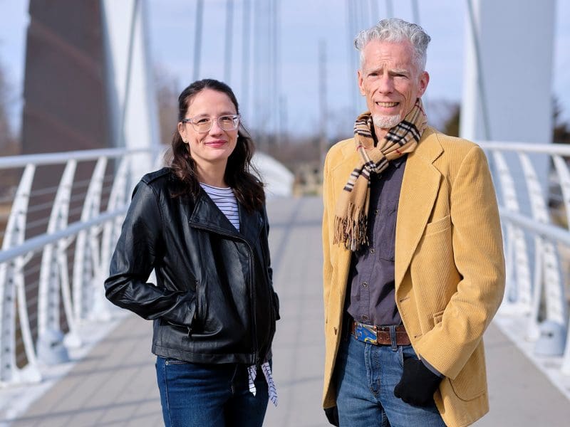 A man and a woman are standing together on a bridge