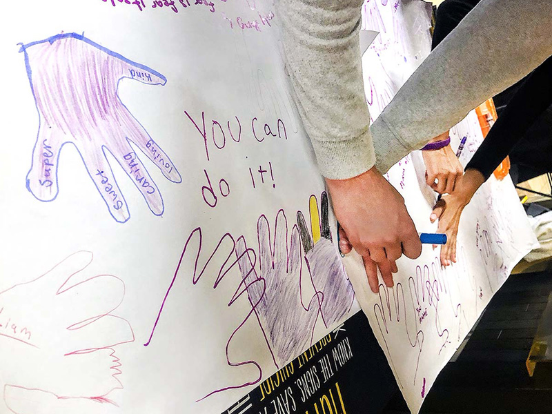 Students trace their hands in purple for Purple Day