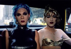 Two femme individuals dressed for clubbing ride in the back of a cab.