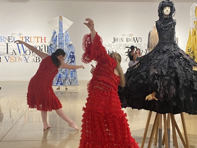 Dancers perform among works of art in a gallery.