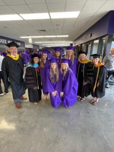 A photo of 9 people in graduation robes.