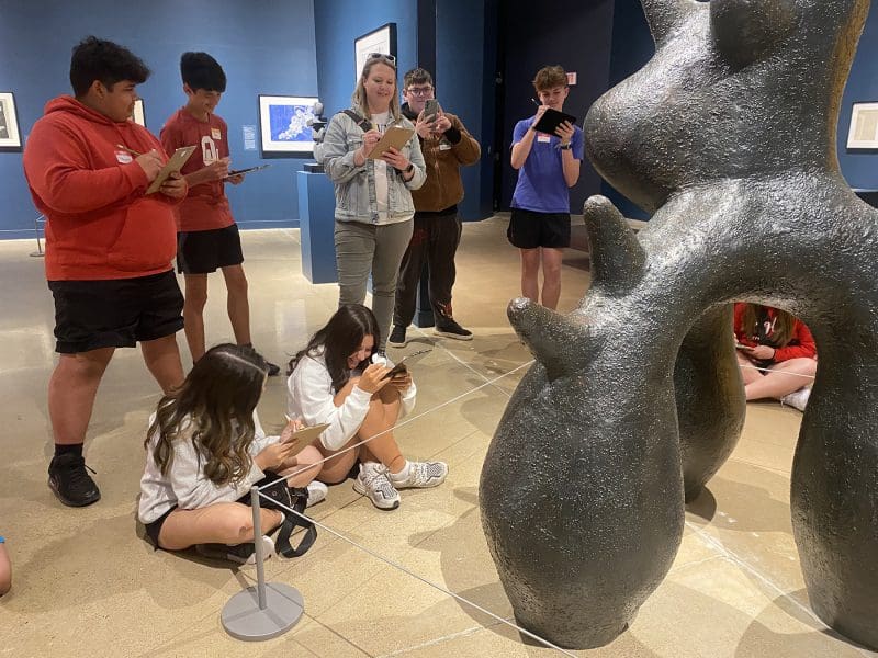 A group of young people and one adult sketch a sculpture in the Ulrich Museum's Polk/Wilson Gallery.