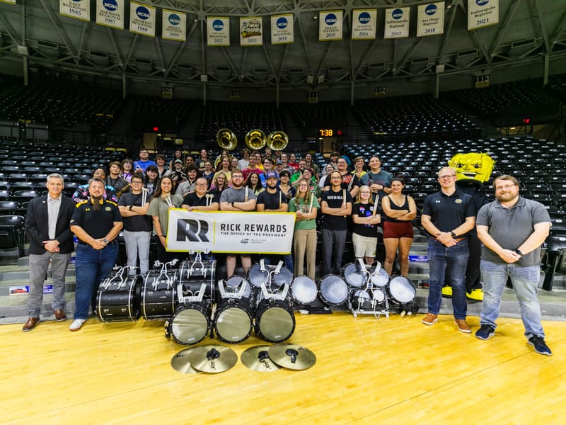 President Rick Muma poses with Shocker Sound Machine in Charles Koch Arena for Rick Rewards