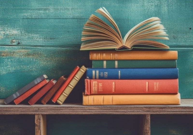 Stack of books on bench. Top book is opened.