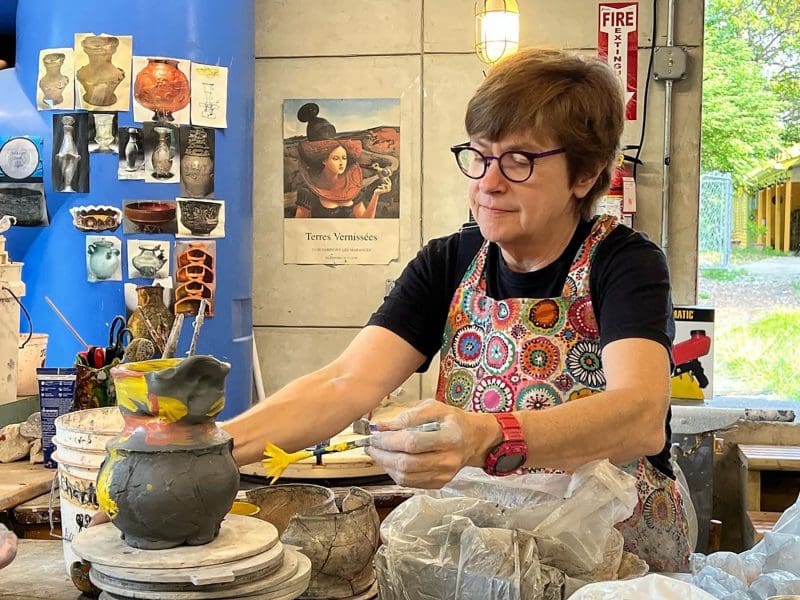 A female artist works on a ceramic pot in her studio.