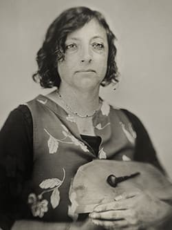 Tintype of a sitting Joanne Price holding a piece of wood.