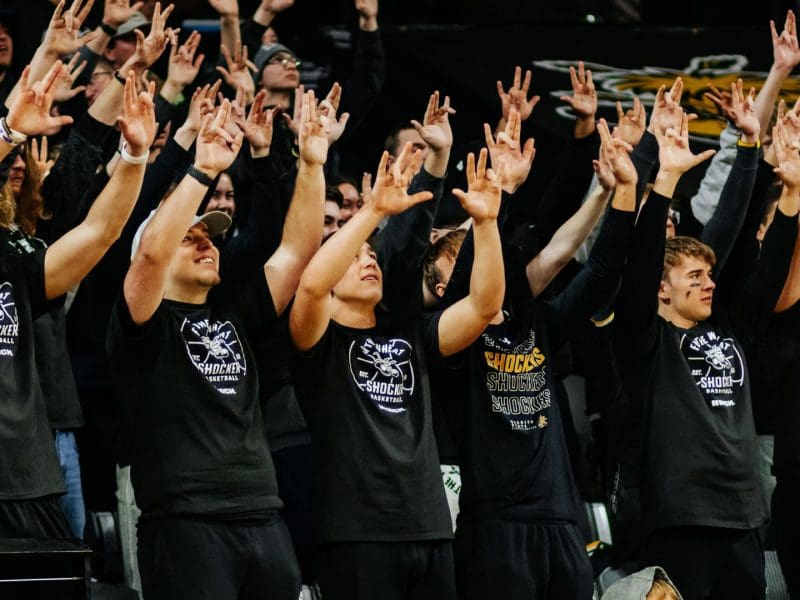 A large group of students cheers on the basketball team in the student section during a men's basketball game