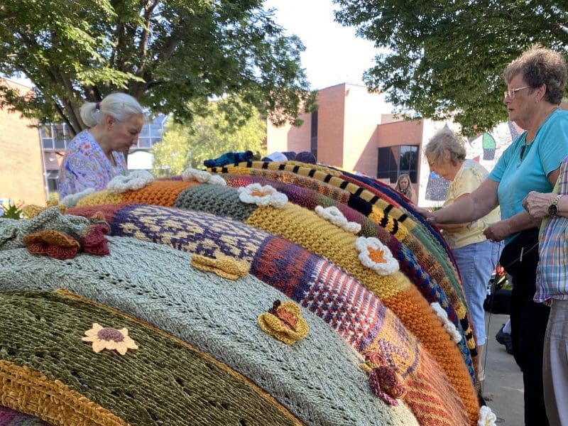 Artists put knitted sections on Tom Ottterness' "Millie" sculpture.