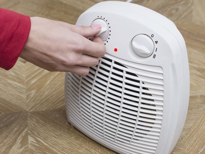 A person turning on a space heater