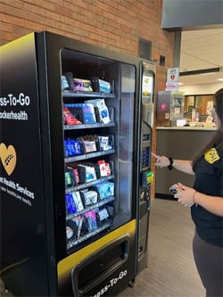 A student grabs an item from the Wellness-to-Go vending machine