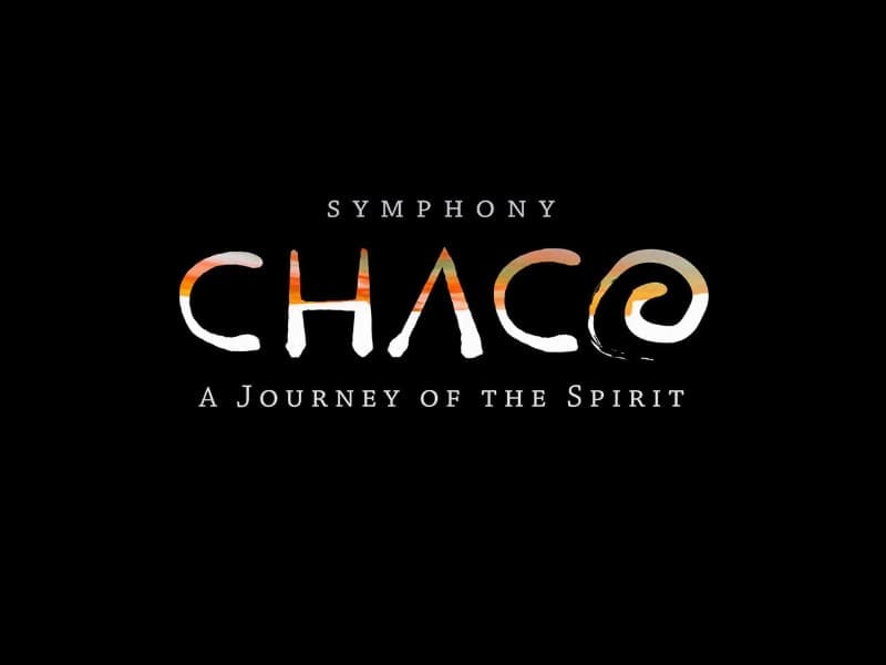 The image contains the title of a symphonic work, "Symphony Chaco: A Journey of the Spirit."  The word "Symphony" is written in small, white, uppercase letters centered at the top. Below "Symphony," the word "Chaco" appears in large, stylized letters with a gradient of orange, white, and black colors that resemble a sunset or natural landscape. The letter "C" at the beginning of "Chaco" is shaped like a crescent, and the letter "O" at the end includes a spiral design, evoking a sense of movement or connection to nature. Below "Chaco," the subtitle reads "A Journey of the Spirit" in smaller white, uppercase letters. The background is entirely black, making the text and designs stand out prominently. This design suggests a theme of spirituality, nature, and exploration, aligning with the artistic and cultural elements likely conveyed in the symphony.