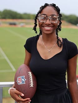 Ja'Nae McKelvy smiles at the camera while holding an NFL football.